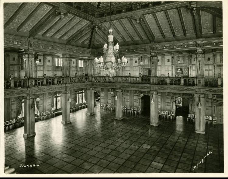 A multi-story ballroom with a tiered chandelier and tiled floor.