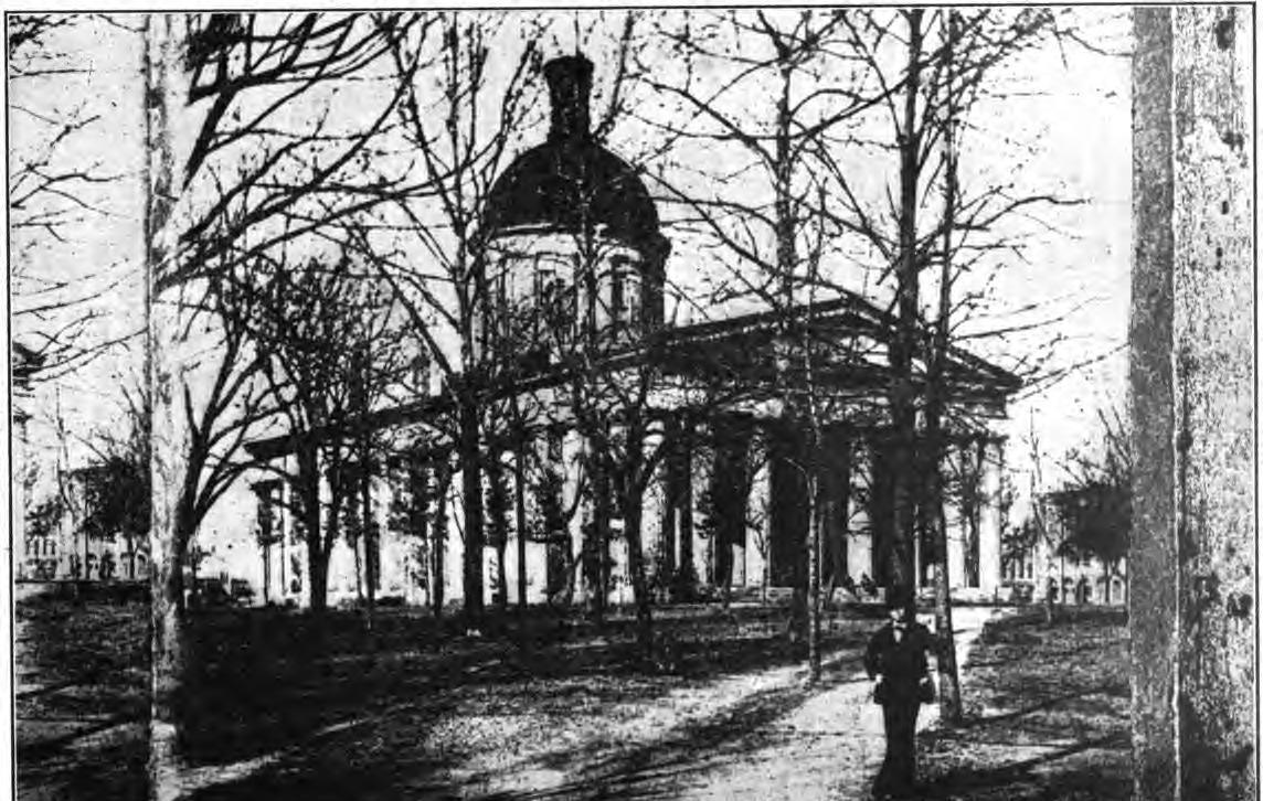 Exterior of a Greek Revival style government building with thick columns that encircle the building. It is topped by a dome.
