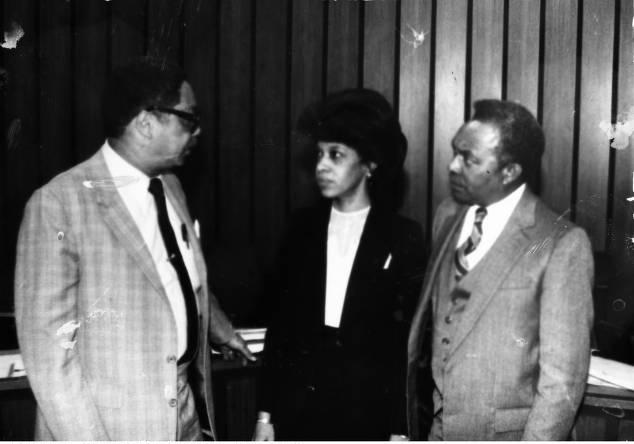 Three people stand next to each other.