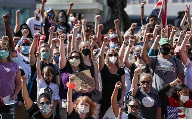 A crowd of protestors all raise up a fist.