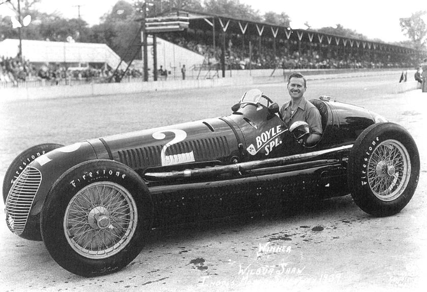 A man sits in an open top race car with the number 2 painted on the side.