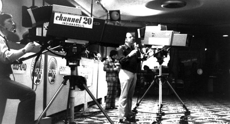 Two men operate two large cameras. One camera says "Channel 20" on the side. 