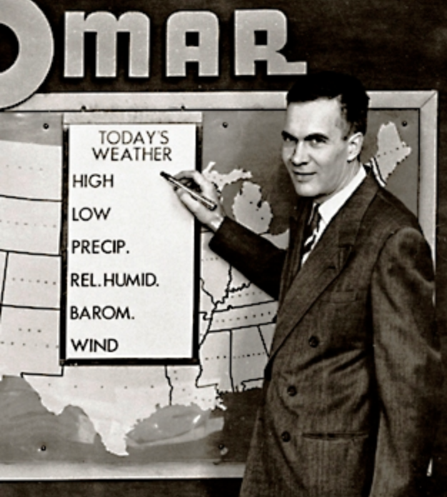 A man stands in front of and points to an old-fashioned weather map.