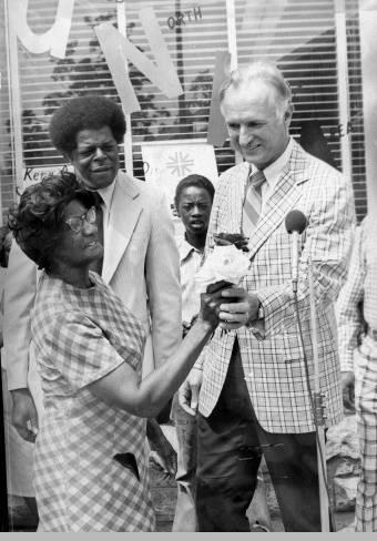 Mayor Hudnut stands with a group of people. He is holding a woman's hand.