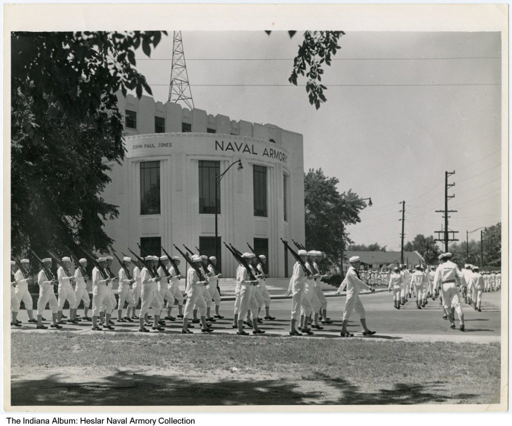 A group of soldiers march in rows in front of the Naval Armory.