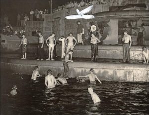 Young men celebrate on the evening of the Japanese surrender ending WWII by jumping into the fountains on Monument Circle, 1945