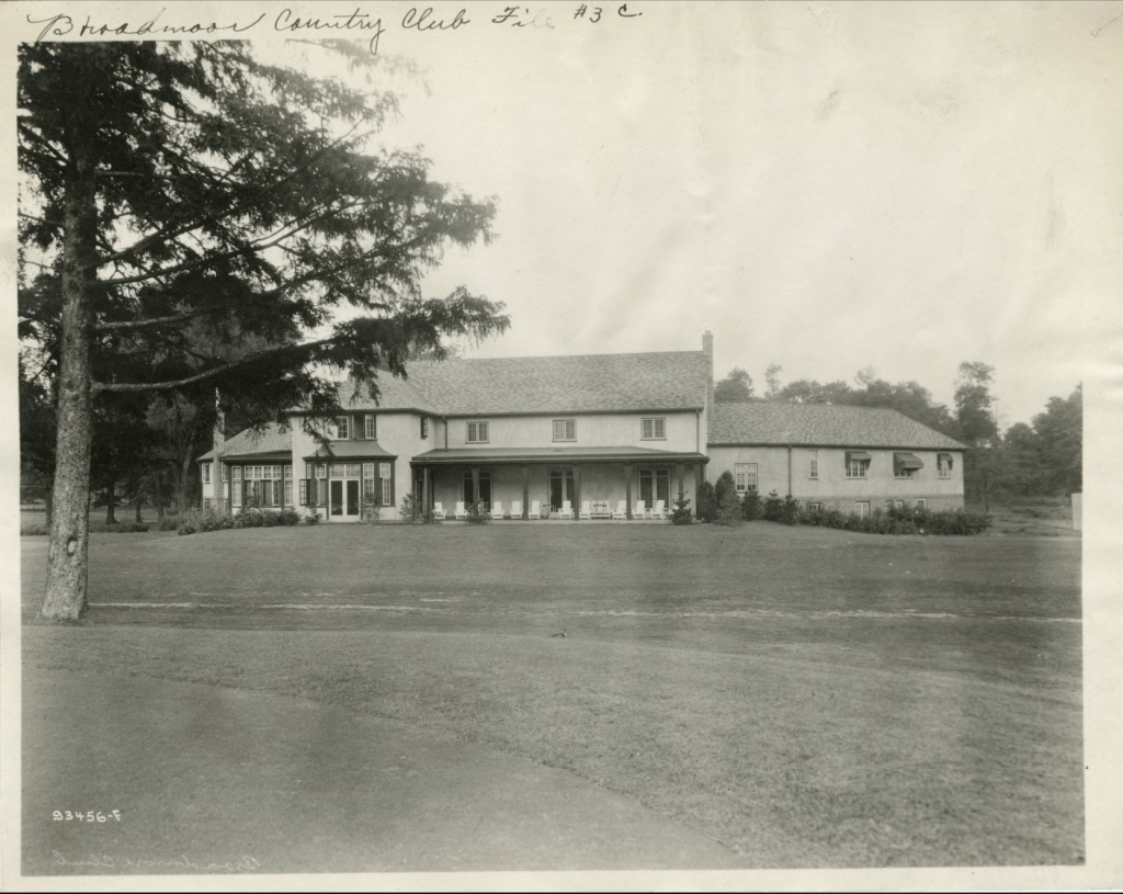 The black and white photo shows the two-story clubhouse on a broad lawn.