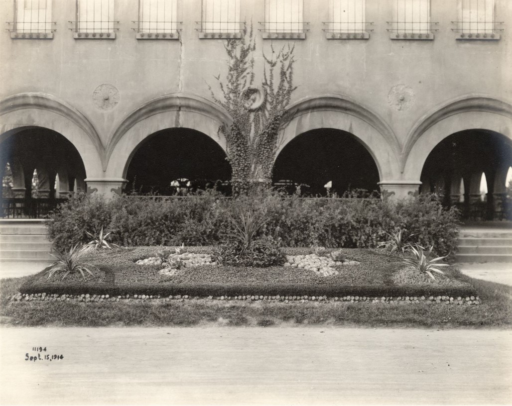 A view of landscaping in front of the arched entryways to a shelter house. 