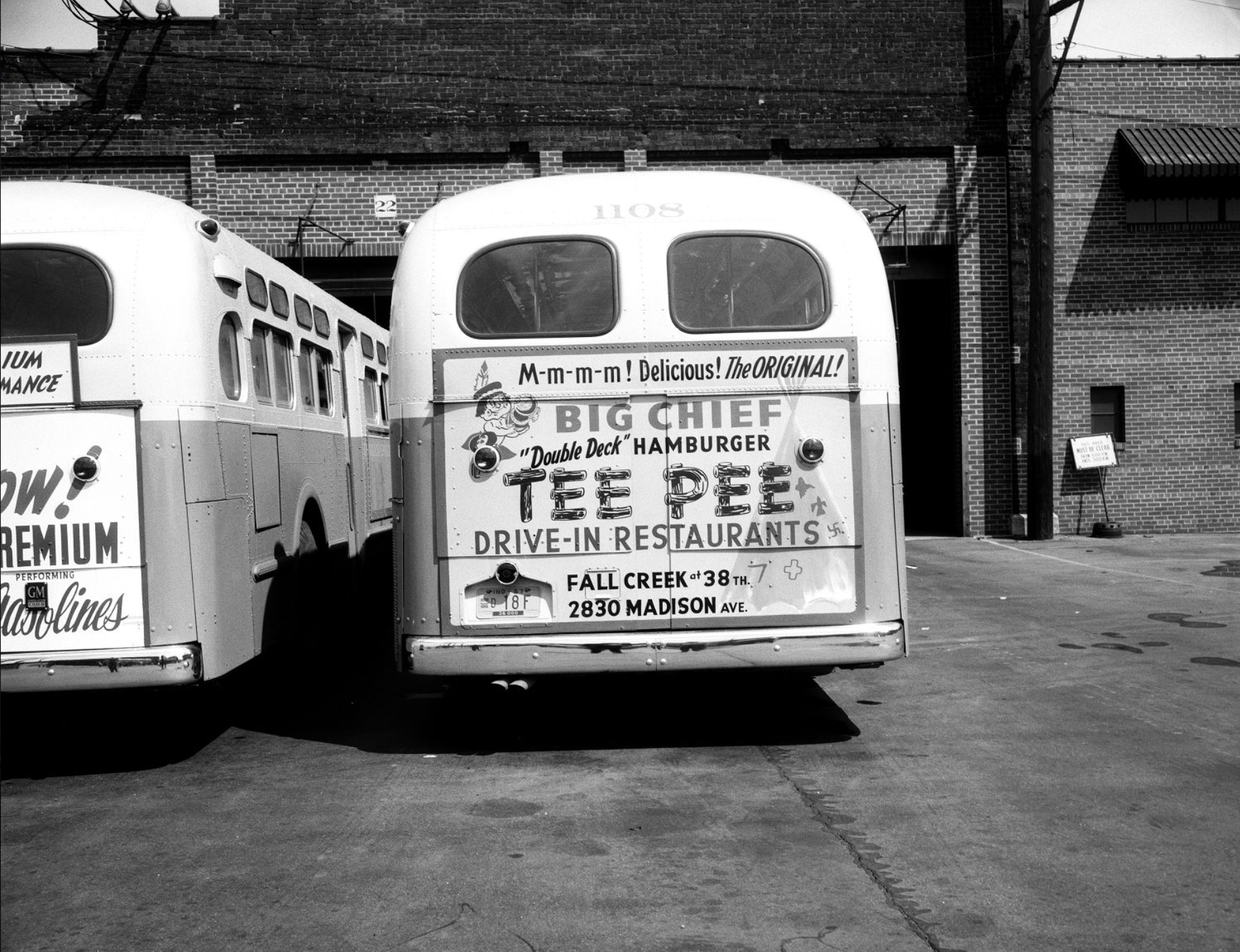 A advertisement on the back of a bus features the Tee Pee Restaurant logo and a caricature of a Native American.