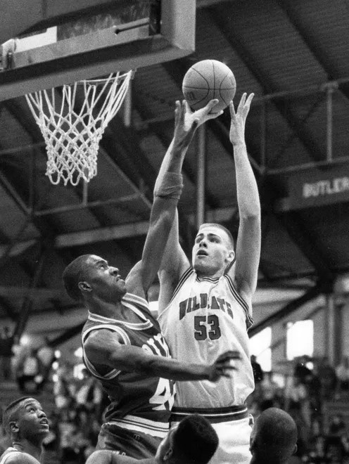 A basketball player tries to block the shot of another player. 