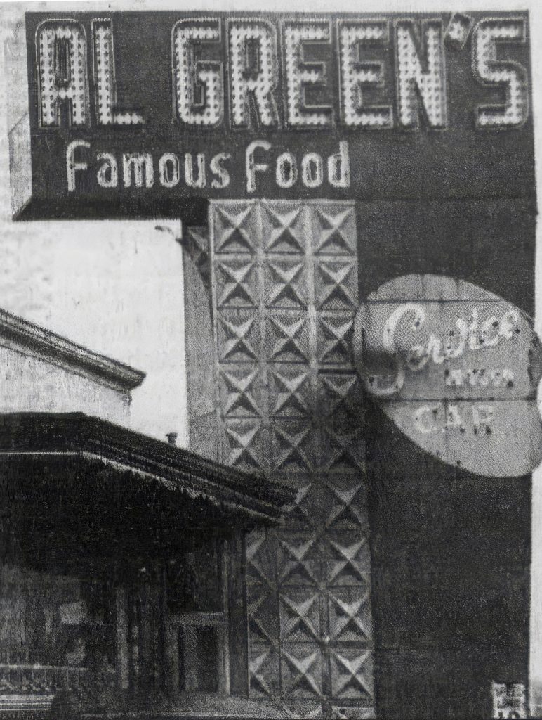 A large sign outside a restaurant. The sign is in the shape of a 7 and reads "Al Green's Famous Food."