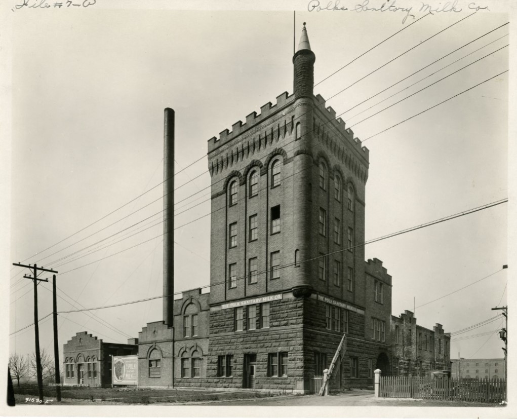 A five story stone and brick building with smaller buildings connected to it on either side. 