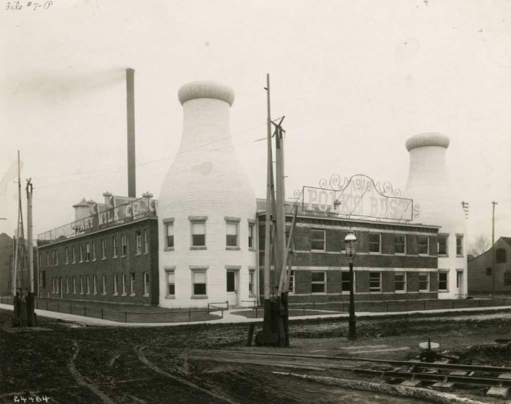 A two story brick building featuring  a milk bottle brick tower on two corners of the building. 