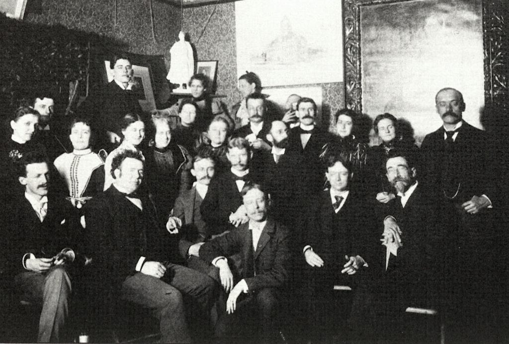 A large group of men and women sit together for a group photo. 