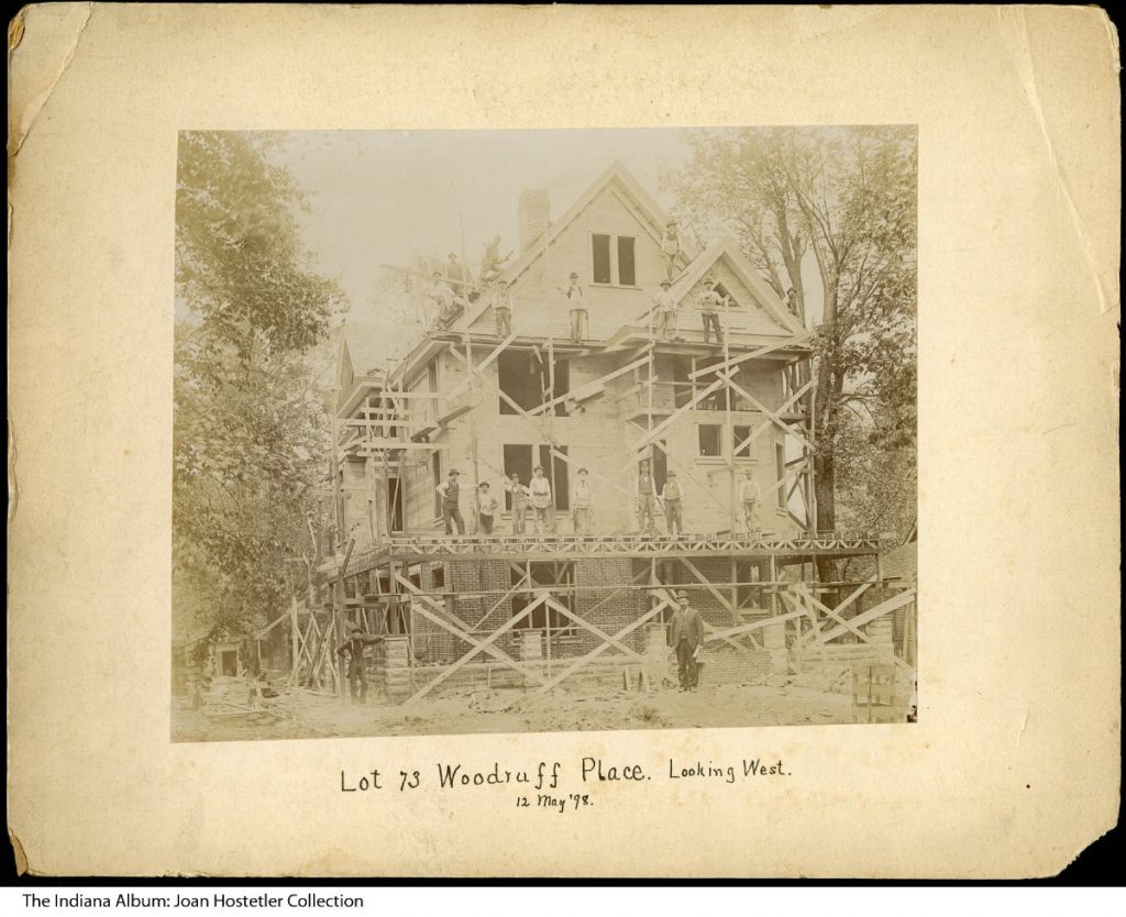 Scaffolding surrounds a partially constructed house. Workers stand on the scaffolding. 