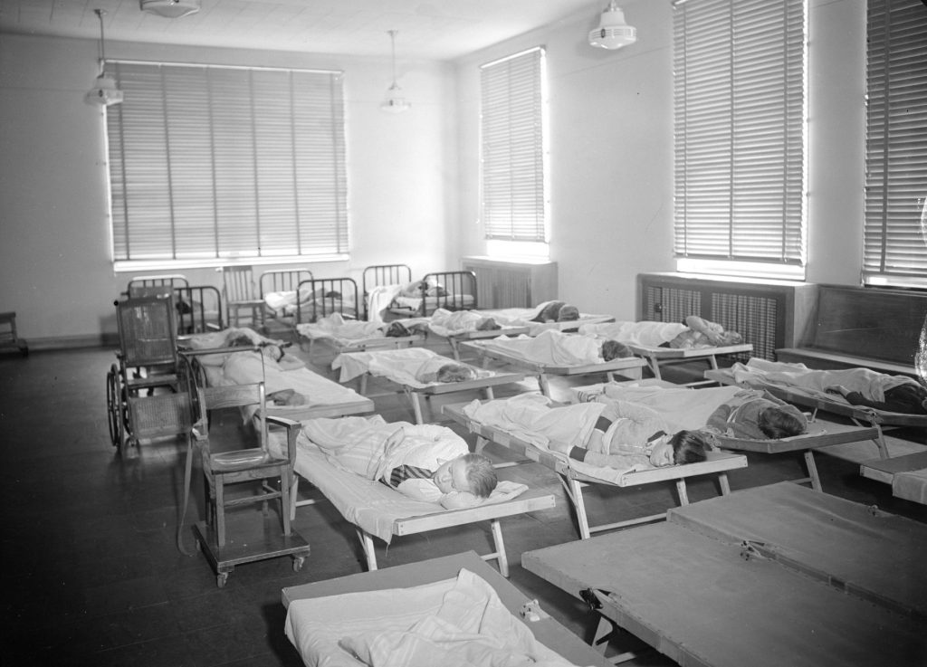 Children take naps on cots and beds at the James E. Roberts School. Wheel chairs are next to two of the cots.