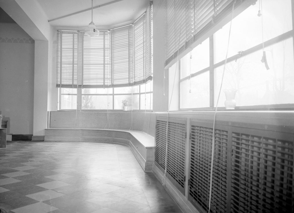 This photo shows a hallway that ends with a rounded window seat in the James E. Roberts School.