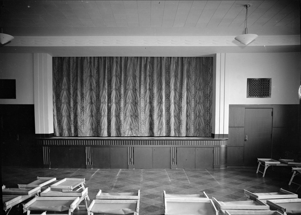 This interior photo of the James E. Roberts School shows a multi-purpose room with a stage.