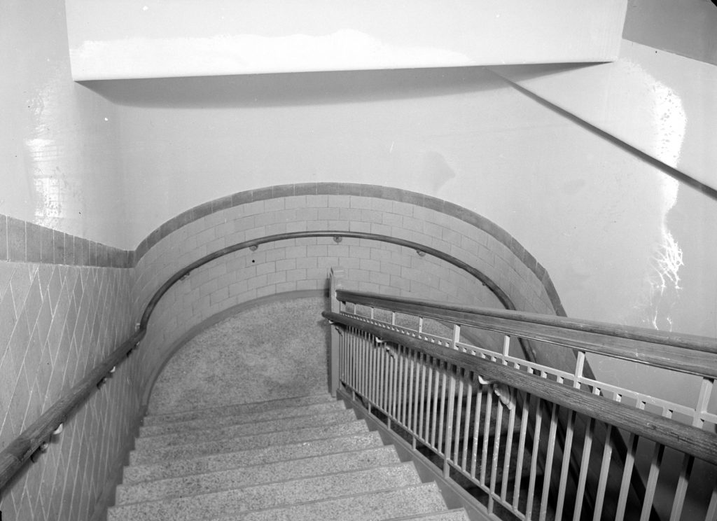 This interior photo of the James E. Roberts School shows a curved stairway with ceramic tile.