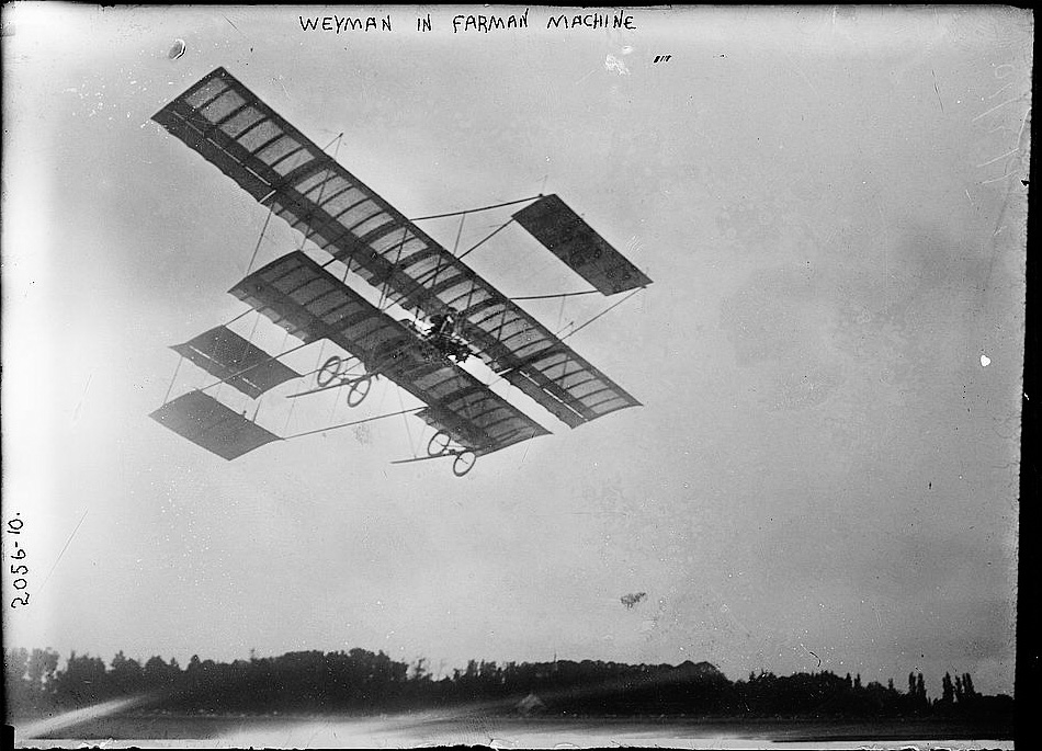 A biplane midflight over a field.