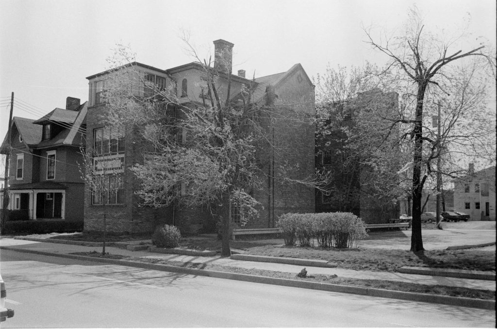A Craftsman Style brick apartment building of 3 stories. The top half-story is wood-trimmed and stuccoed.