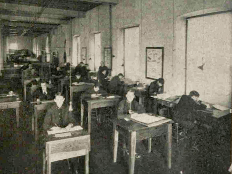Students sit at individual desks in a classroom.