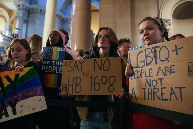 A group of people hold protest signs.