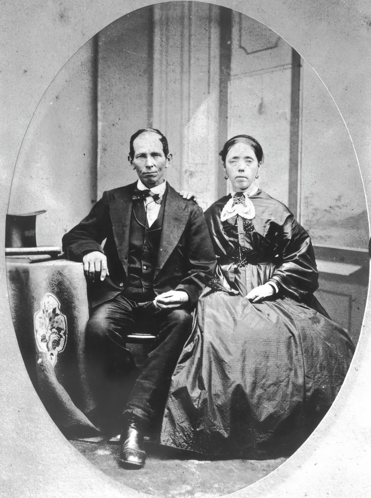 A man and a woman sit next to each other in a staged photograph.