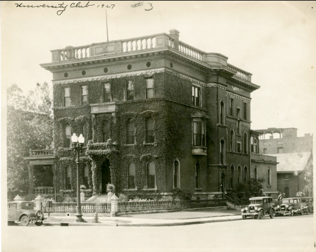 The front of a three-story, brick building. The front of the building is covered in vines.