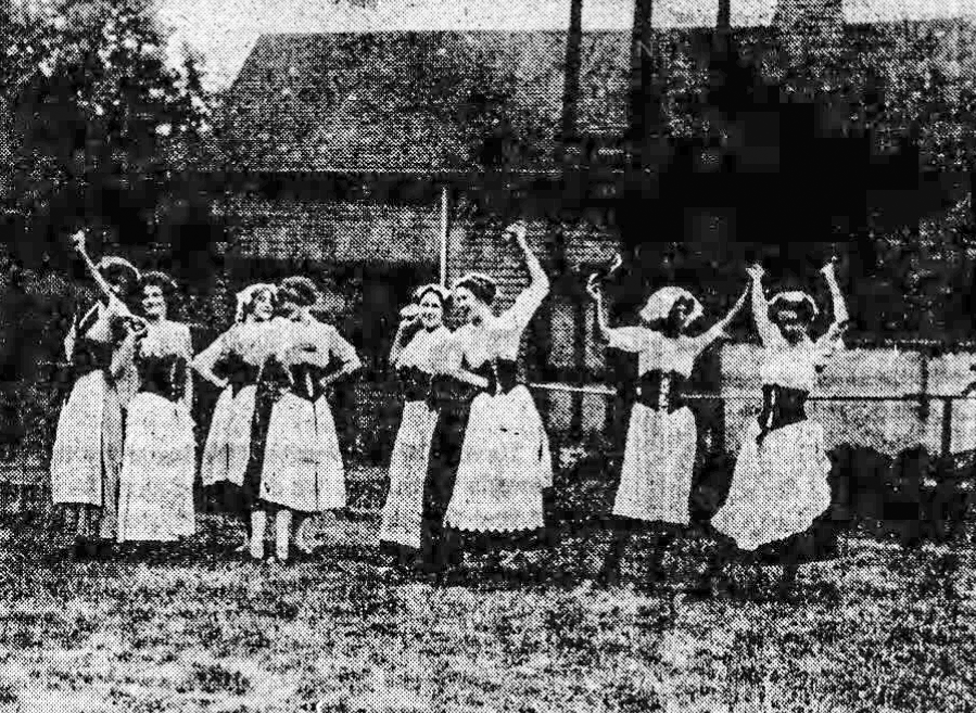 A group of young women dance in a yard outside.