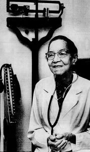 Headshot of an older woman in a doctor's white jacket with a stethoscope hanging from her neck.