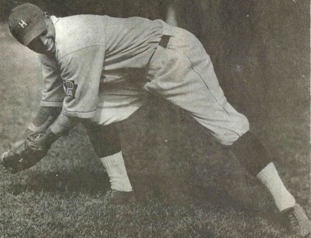 A baseball player is bent over catching a low ball.
