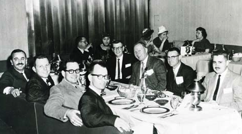 A group of men are seating around a dining table.