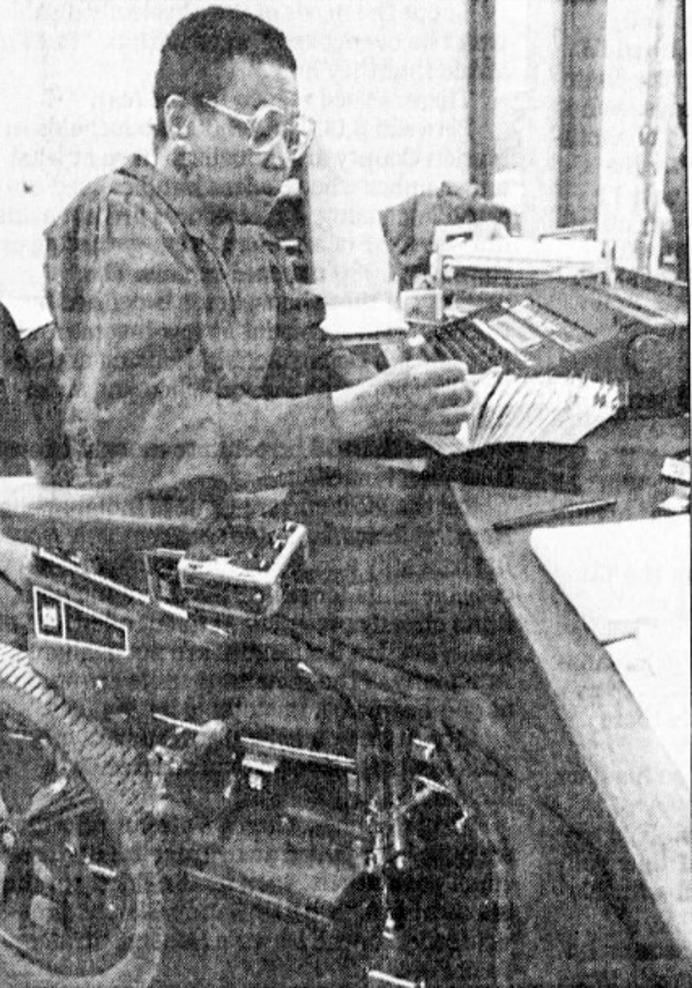 A woman in a wheelchair sits at a desk and riffles through a set of index cards.