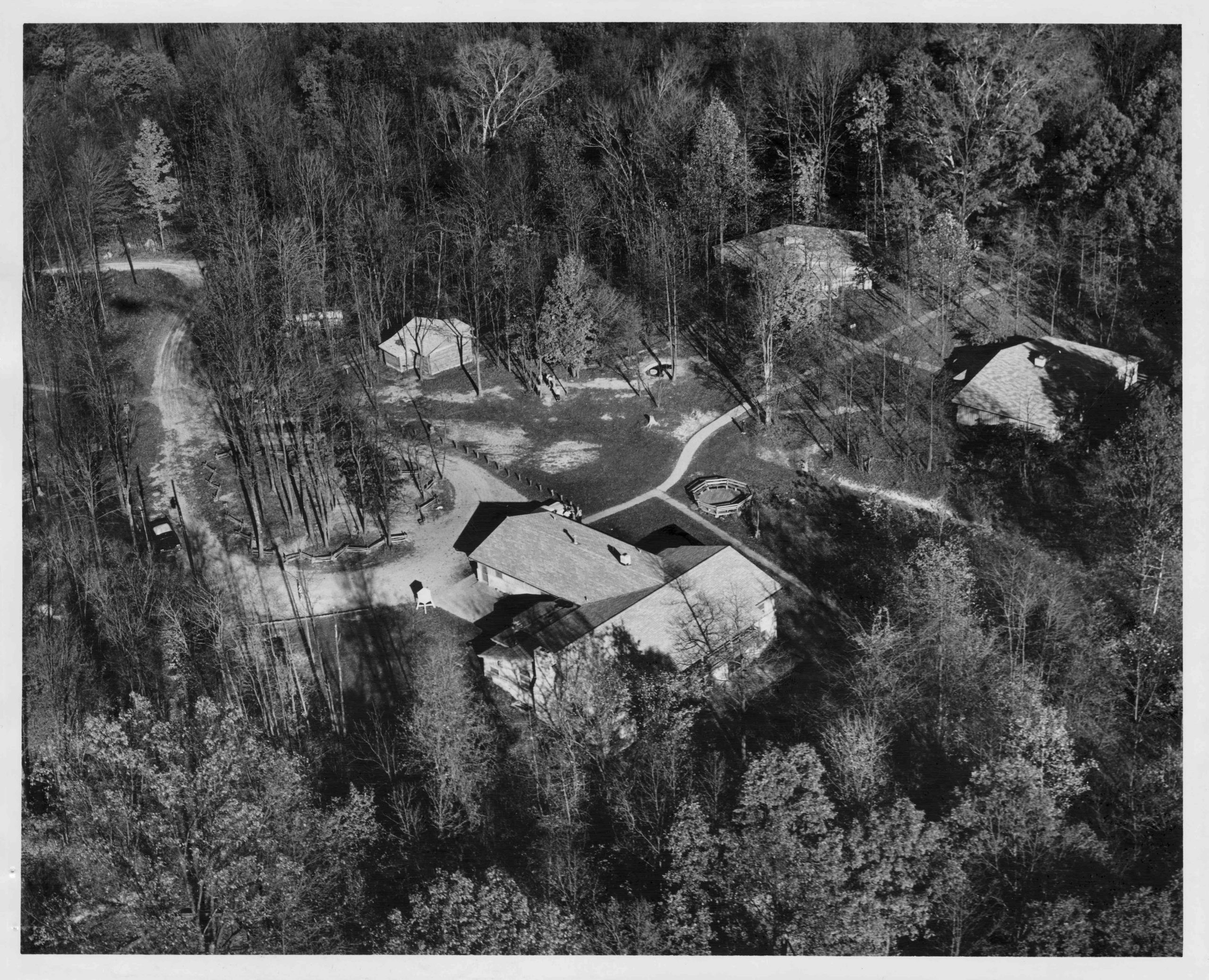 Aerial view of of several buildings strewn across a heavily wooded area.
