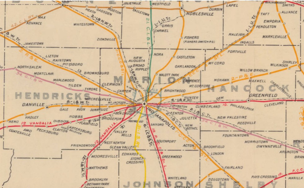 Historical railroad map of central Indiana centered on Indianapolis, showing rail lines radiating outward through Marion County and surrounding counties, with labeled towns including Carmel, Noblesville, Brownsburg, Clermont, Lawrence, Greenwood, and Mooresville. Colored rail routes and county names are marked on a beige background.