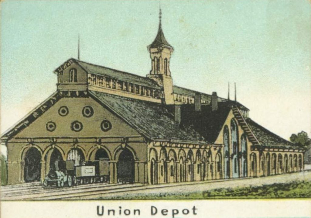 Illustration of Union Depot, a large historic train station with arched entrances, rows of tall windows, and a central tower rising above the roof. The caption “Union Depot” appears below the building.