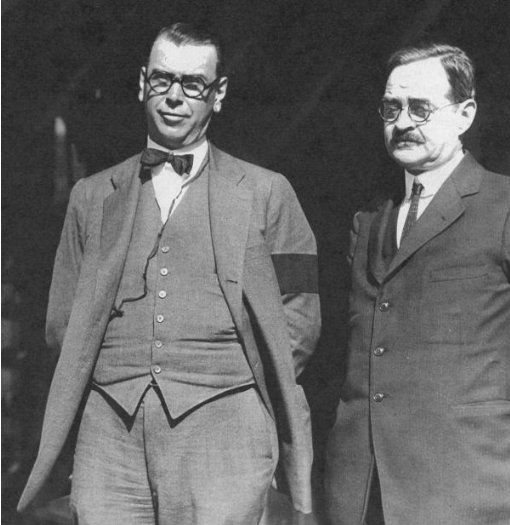 Two men stand next to each other.