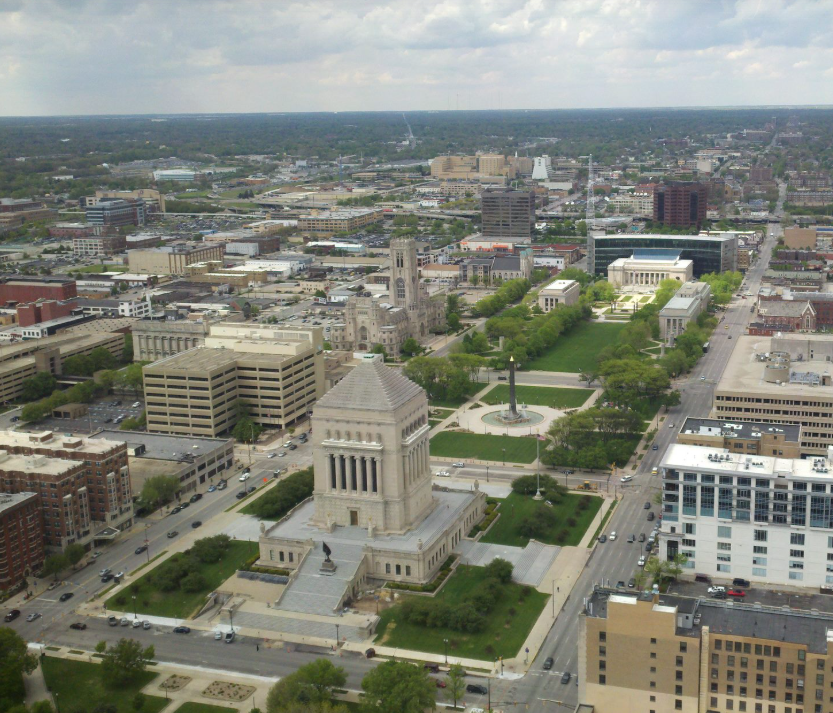 Aerial view of a multi-block plaza with large government buildings on either side and a tall, skinny memorial in the middle.
