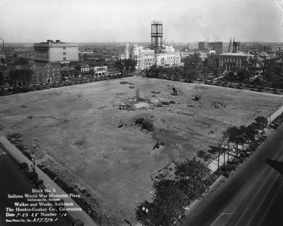 Historic black-and-white aerial photograph of Block No. 5 of the Indiana World War Memorial Plaza in Indianapolis. The image shows a large cleared construction site occupying an entire city block, with excavated earth, construction debris, and a few foundation elements visible near the center.